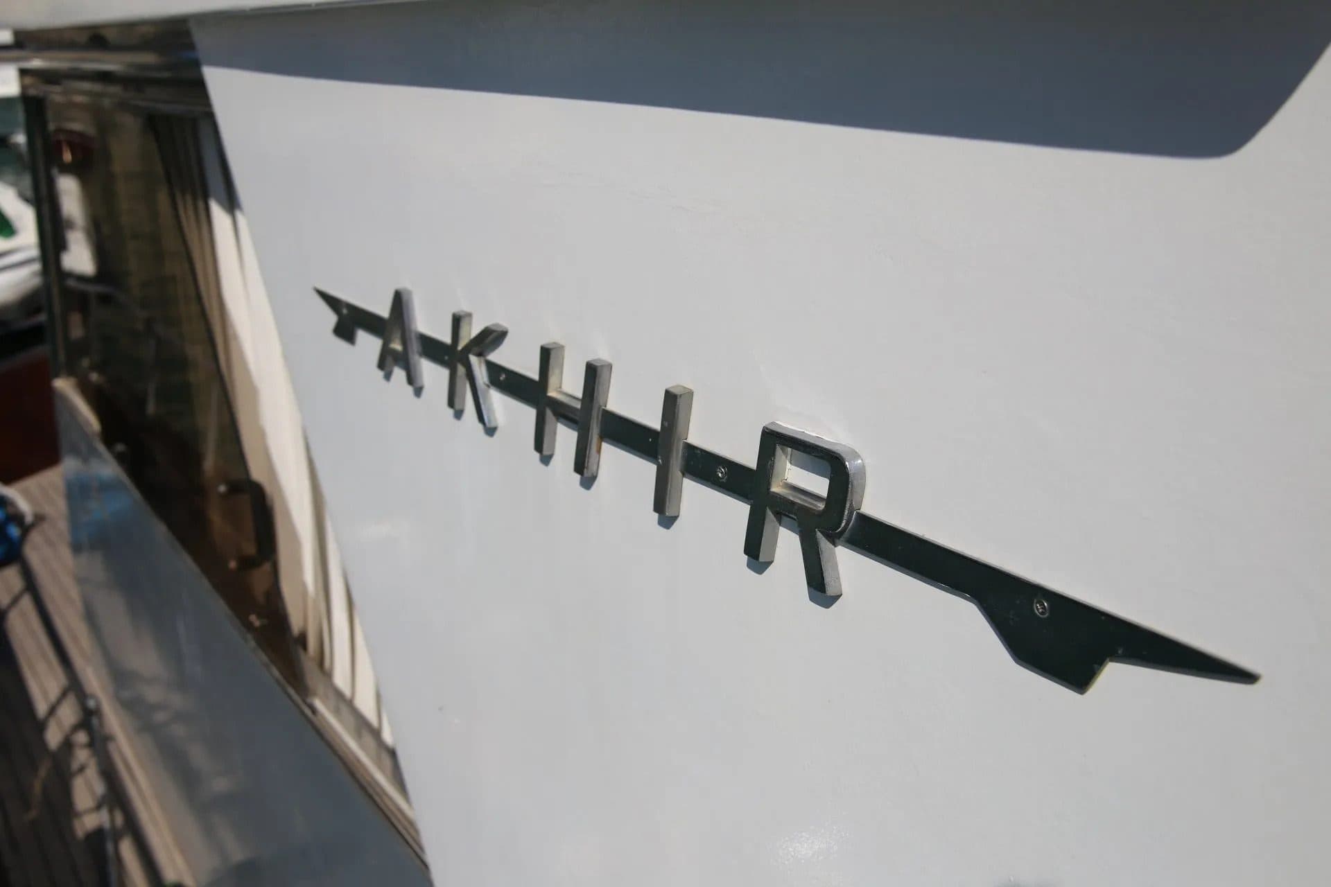 The chrome AKHIR lettering on the hull of a Cantieri di Pisa yacht