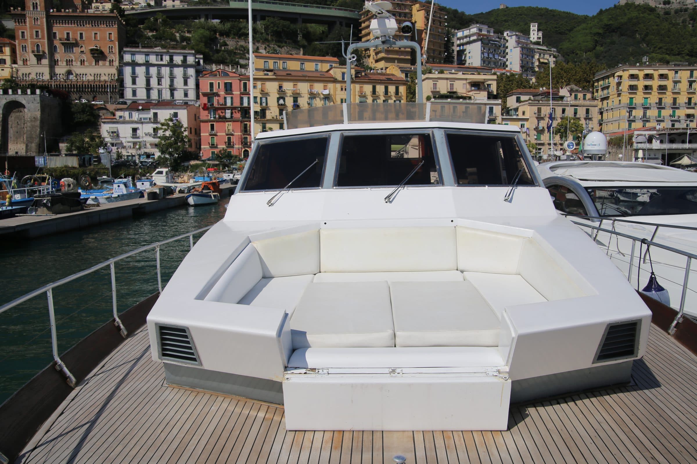 The foredeck sun pad of Antonella IV in the port of Salerno, with the town's coloured houses behind