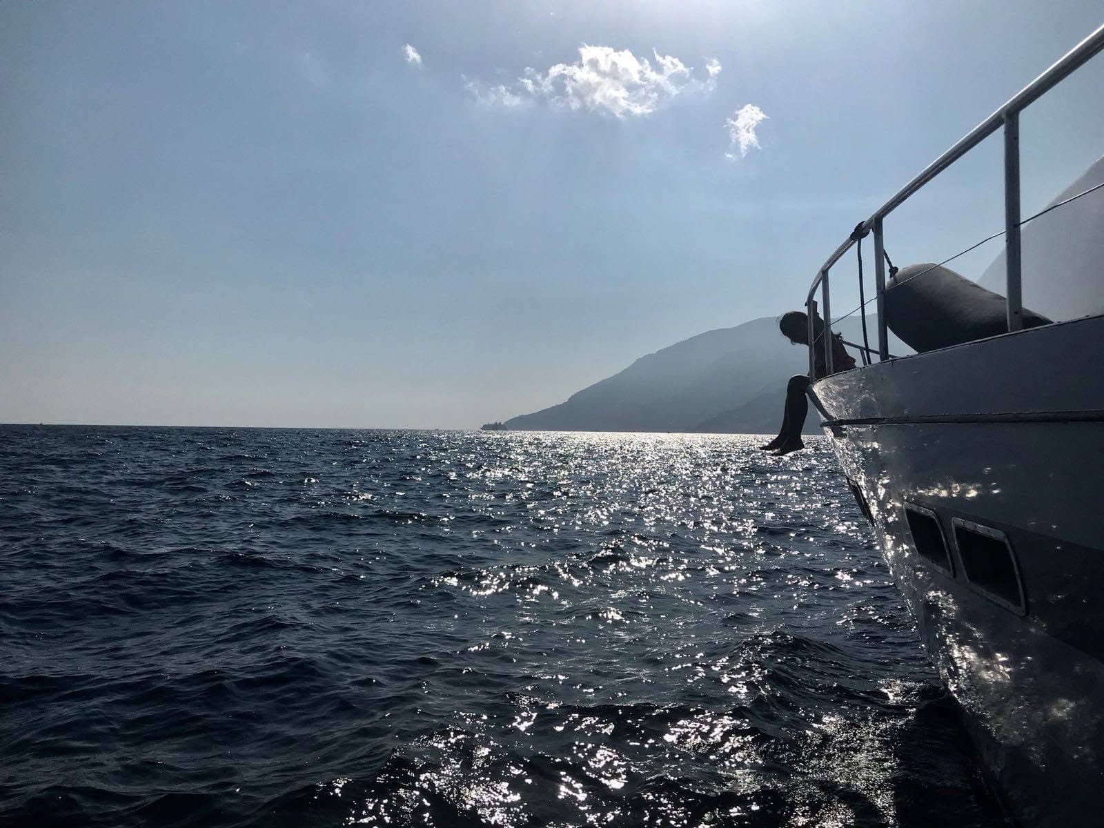 Sunlight on the sea beside the bow of the yacht, with the coast in the distance