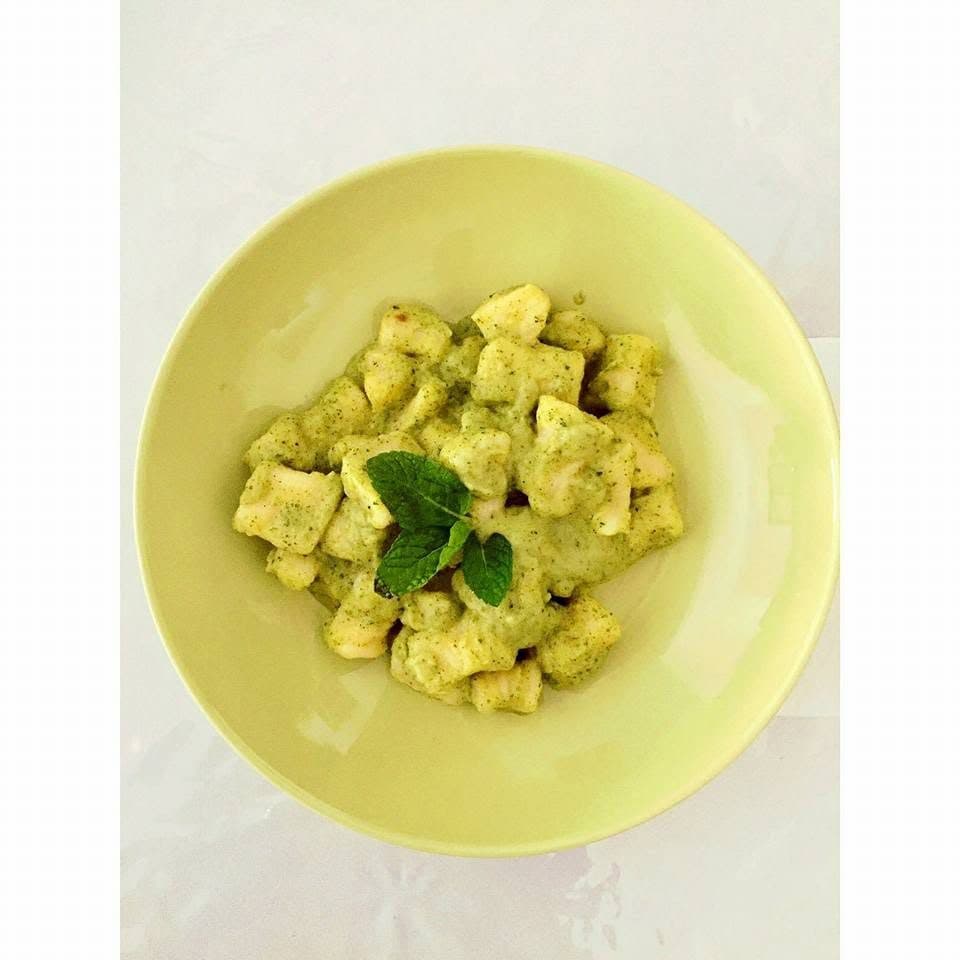 A plate of gnocchi with pesto, cooked on board