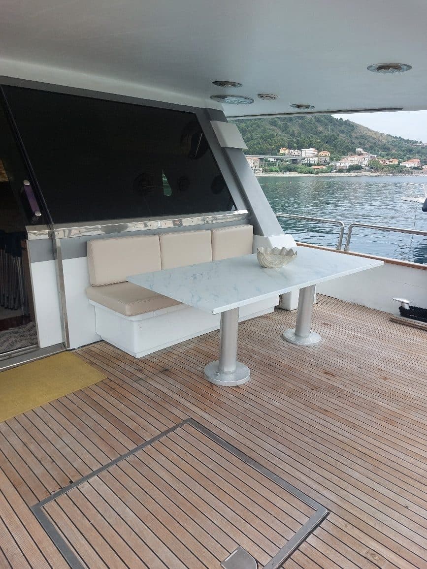 The aft deck of Nikole K with its table and a view of the Cilento coast